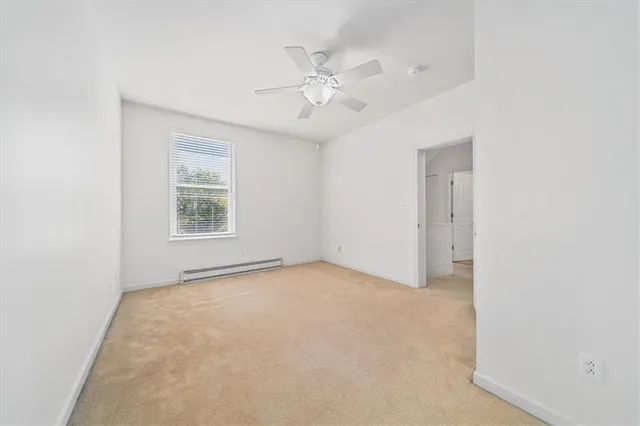 an empty room with a ceiling fan and window