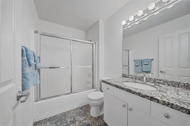 a bathroom with a granite countertop sink toilet a mirror and shower