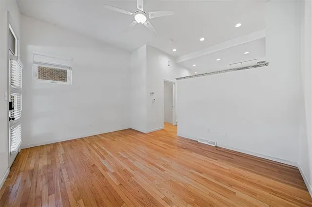 a view of empty room with wooden floor and fan