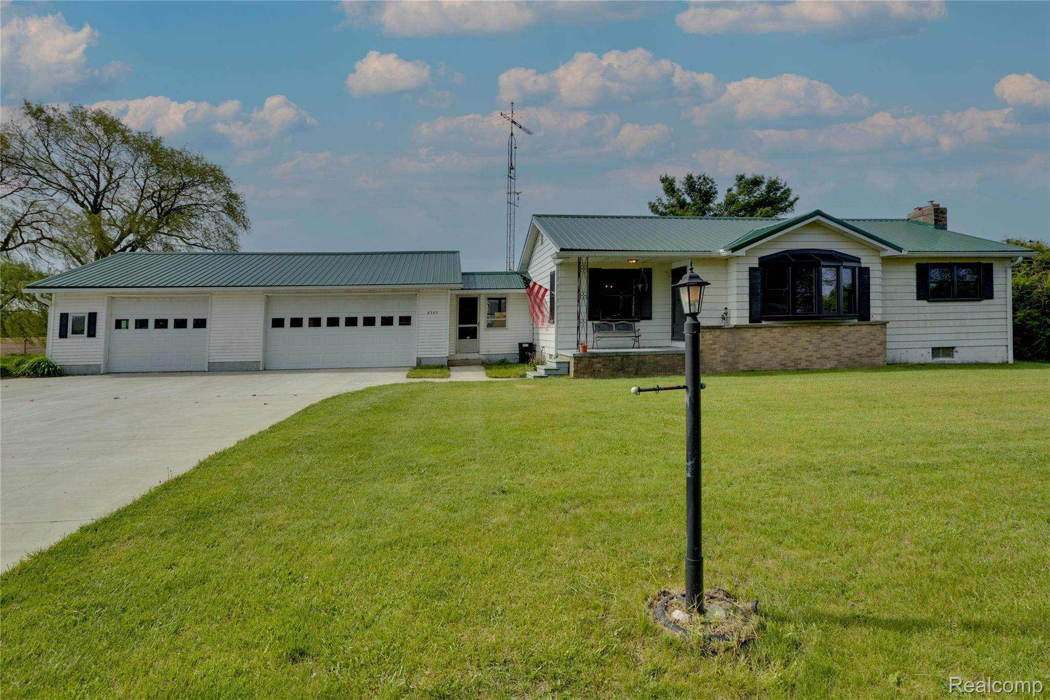 6373 Norman Road Jeddo, MI 48032 - Photo 1 of 32 View of front of house with concrete driveway, a metal roof, a garage, and a front lawn