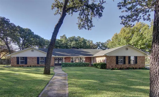 a front view of a house with a garden and trees