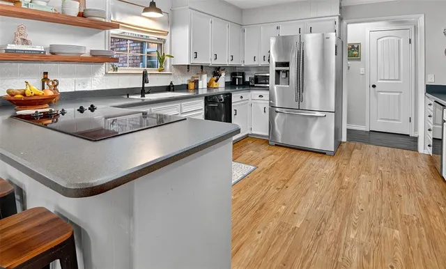 a kitchen with stainless steel appliances granite countertop a refrigerator a stove and a wooden floors