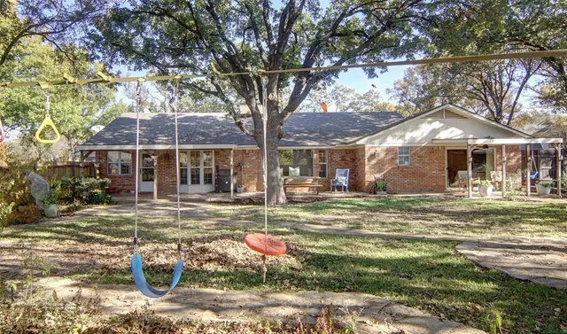 a backyard of a house with table and chairs under an umbrella