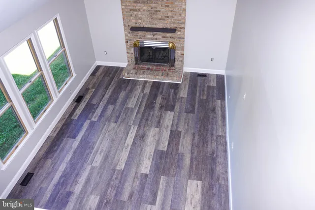 a view of empty room with wooden floor and fireplace