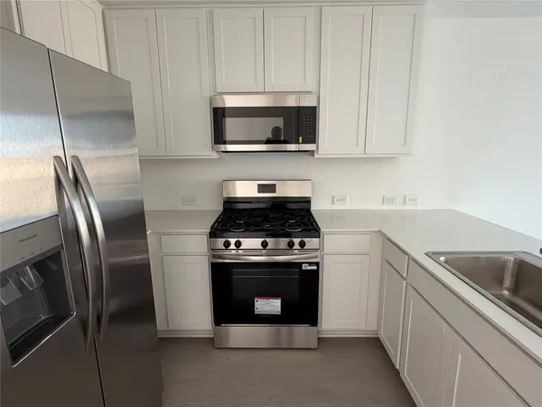 a kitchen with stainless steel appliances granite countertop a stove a refrigerator and a sink