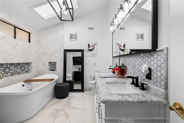 a bathroom with a granite countertop tub sink and mirror