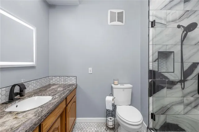 a bathroom with a granite countertop toilet sink and mirror