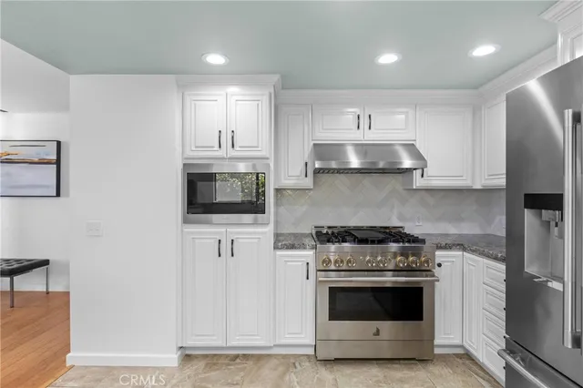 a kitchen with stainless steel appliances white cabinets and stove top oven