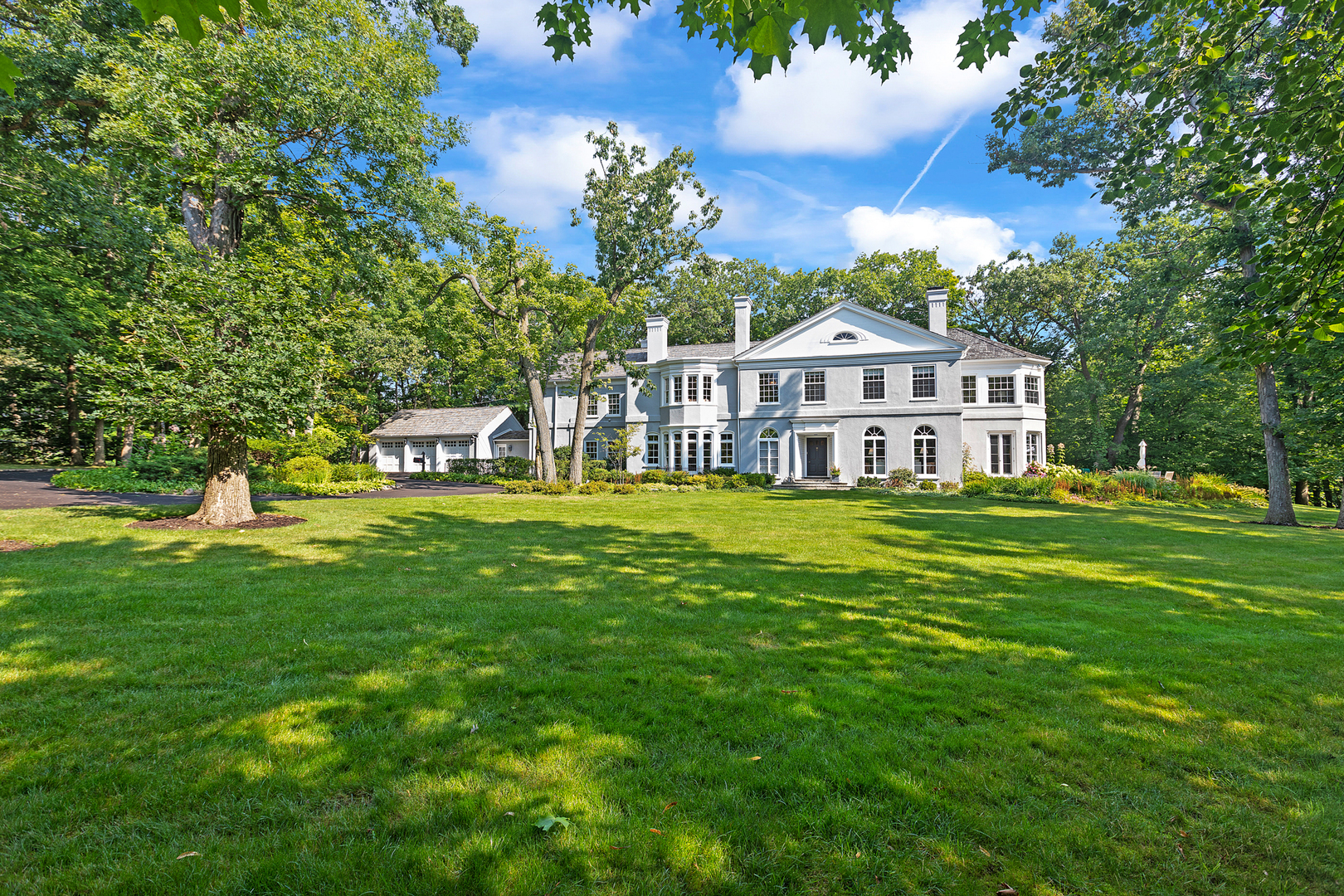 a front view of a house with a garden and trees