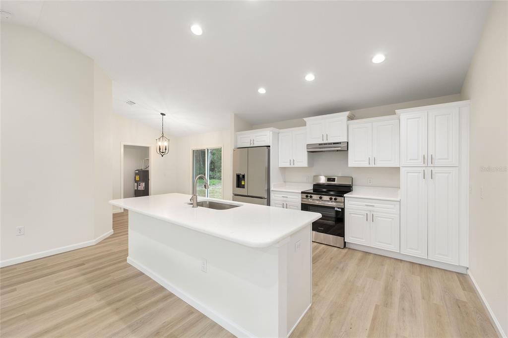 14769 Southwest 24th Place Ocala, FL 34481 - Photo 11 of 33 a large white kitchen with kitchen island a sink white cabinets and stainless steel appliances