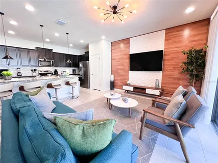 a living room with furniture kitchen view and a wooden floor