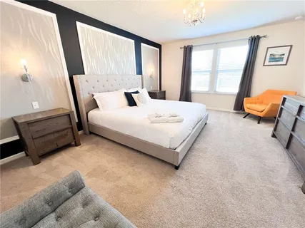 a bedroom with a bed a couch and a flat tv screen on the dresser