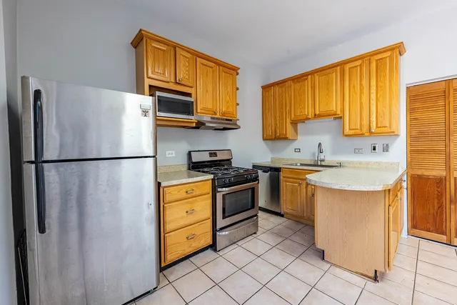 a kitchen with stainless steel appliances granite countertop a refrigerator a sink dishwasher a stove with wooden cabinets