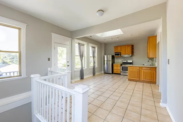 a large white kitchen with cabinets a sink a window and stainless steel appliances