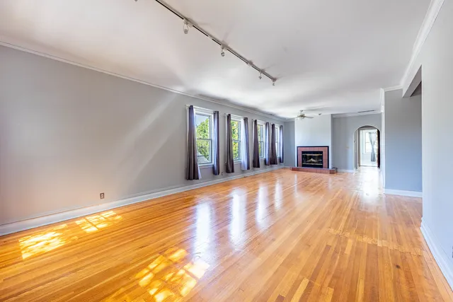 a view of an empty room with window and wooden floor