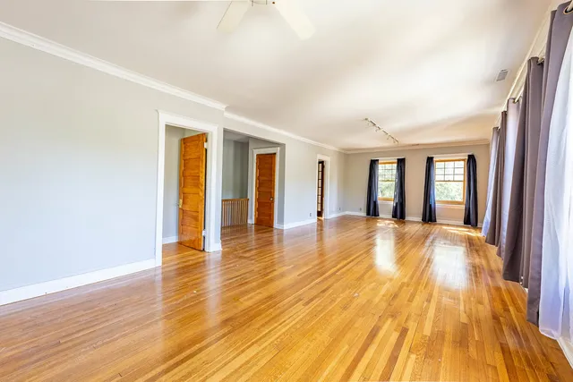 a view of an empty room with wooden floor and a window
