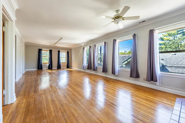 a view of an empty room with window and wooden floor