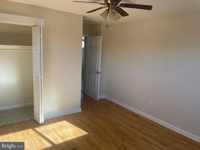 an empty room with wooden floor closet and windows