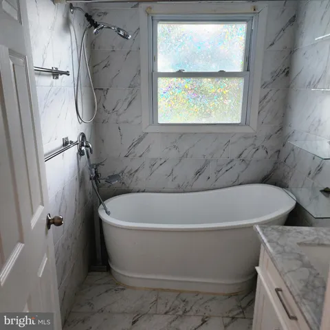 a white bath tub sitting in a bathroom next to a window