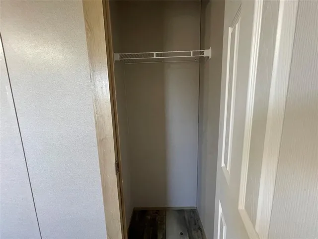 a view of a hallway with wooden floor and a bathroom