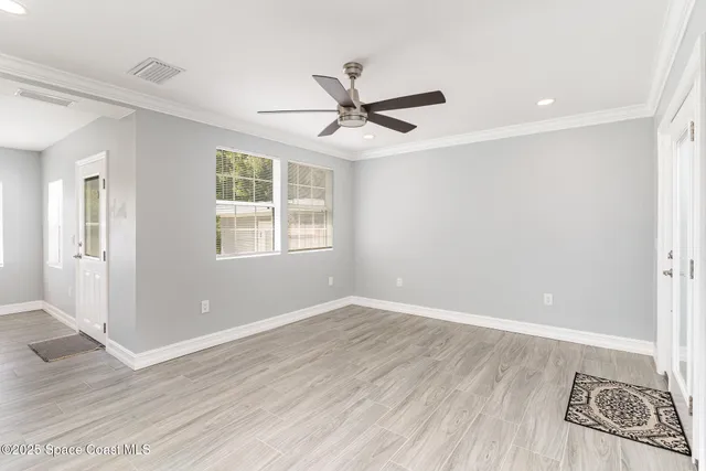 an empty room with wooden floor ceiling fan and windows