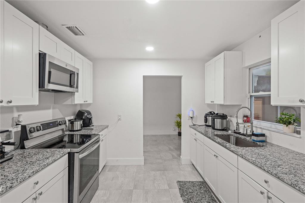 13002 East Wheeler Road Dover, FL 33527 - Photo 8 of 22 a kitchen with granite countertop a sink stove and cabinets