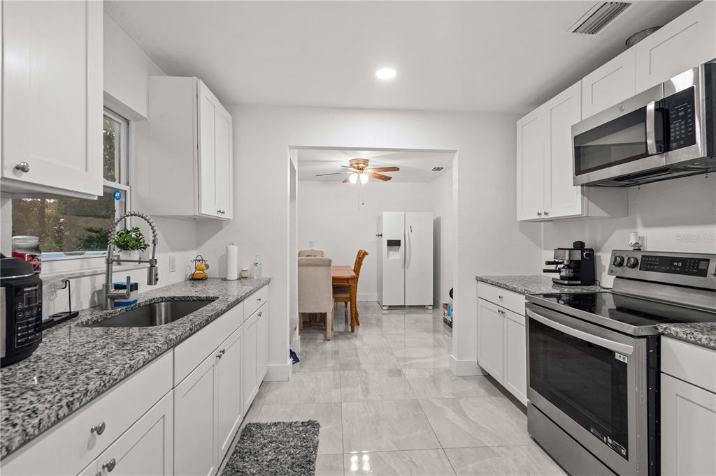 13002 East Wheeler Road Dover, FL 33527 - Photo 9 of 22 a kitchen with stainless steel appliances granite countertop a sink stove and cabinets