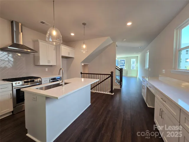 a kitchen with stainless steel appliances granite countertop a sink a stove and a wooden floors