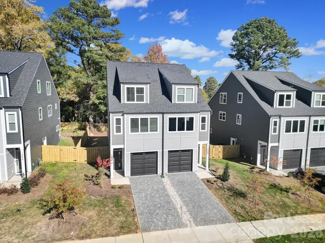 a view of a white house with large windows next to a road