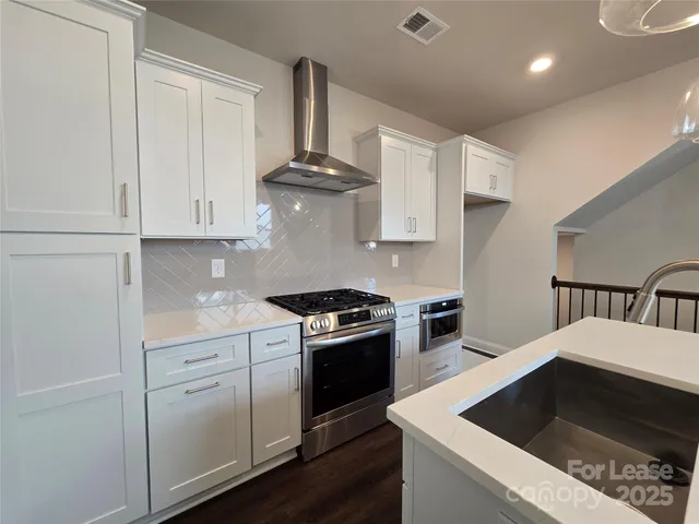 a kitchen with stainless steel appliances granite countertop a stove a sink and a microwave