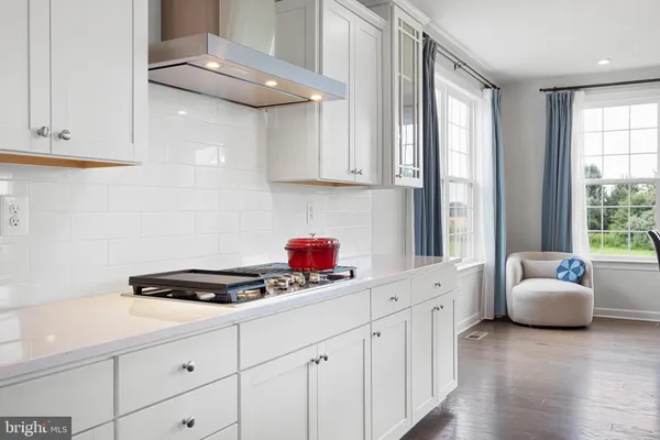 a kitchen with stainless steel appliances a sink dishwasher stove and white cabinets with wooden floor