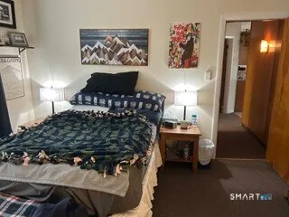 a bedroom with a bed and a lamp on dresser