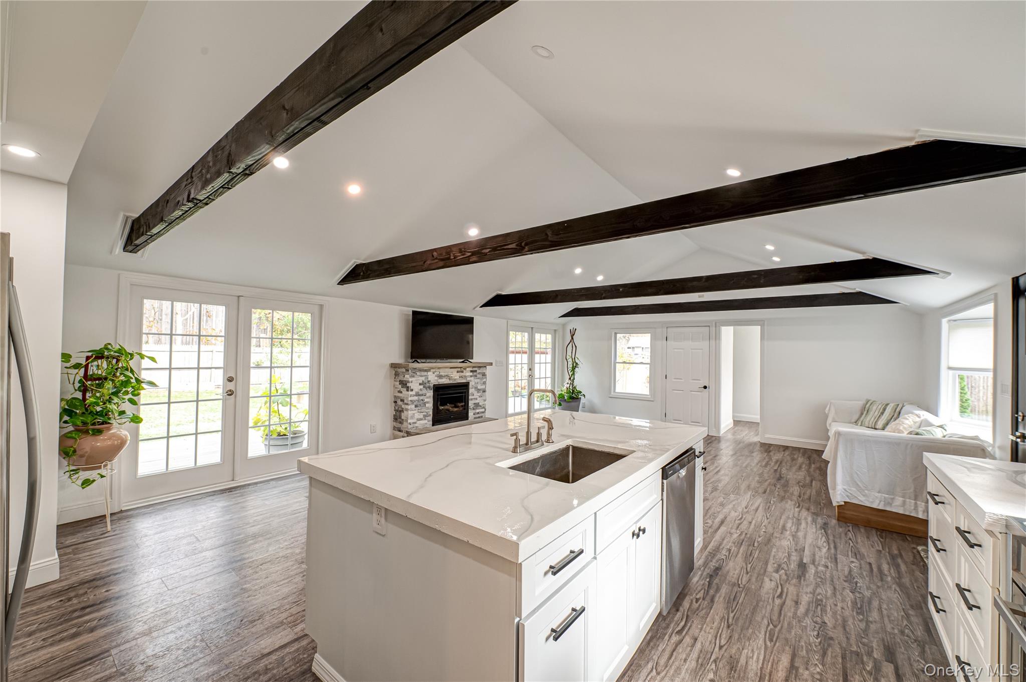 39 Lynncliff Road Hampton Bays, NY 11946 - Photo 34 of 34 Kitchen with open floor plan, dark wood finished floors, an island with sink, white cabinetry, and a fireplace