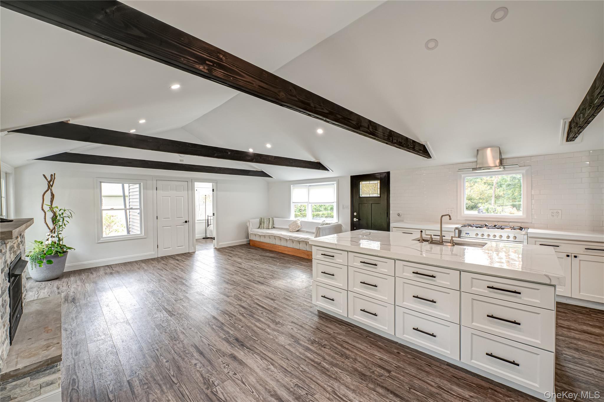 39 Lynncliff Road Hampton Bays, NY 11946 - Photo 32 of 34 Kitchen with white cabinetry, open floor plan, a center island with sink, dark wood-type flooring, and recessed lighting