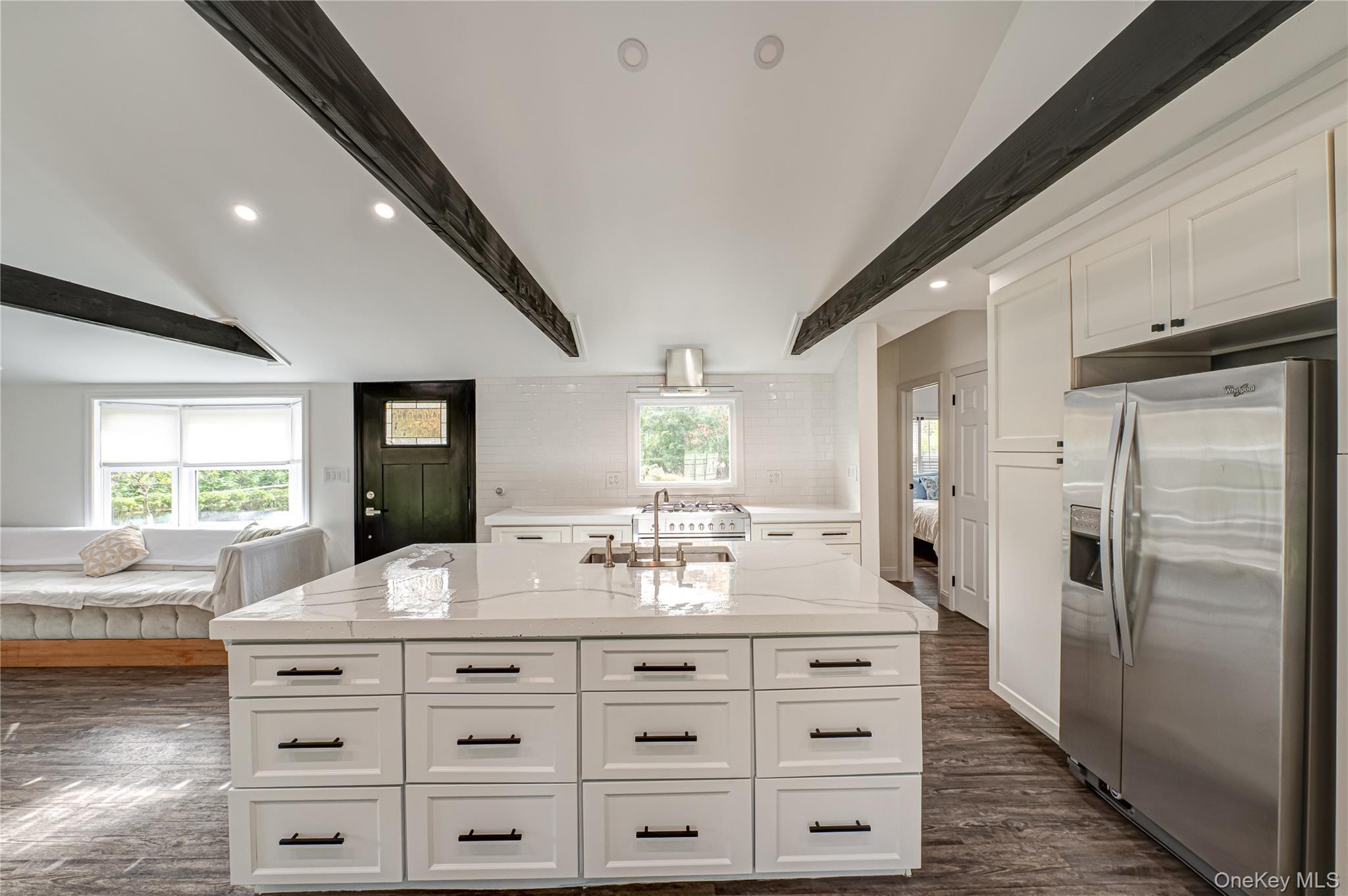 39 Lynncliff Road Hampton Bays, NY 11946 - Photo 8 of 34 Kitchen featuring stainless steel refrigerator with ice dispenser, light stone countertops, a center island, white cabinets, and recessed lighting