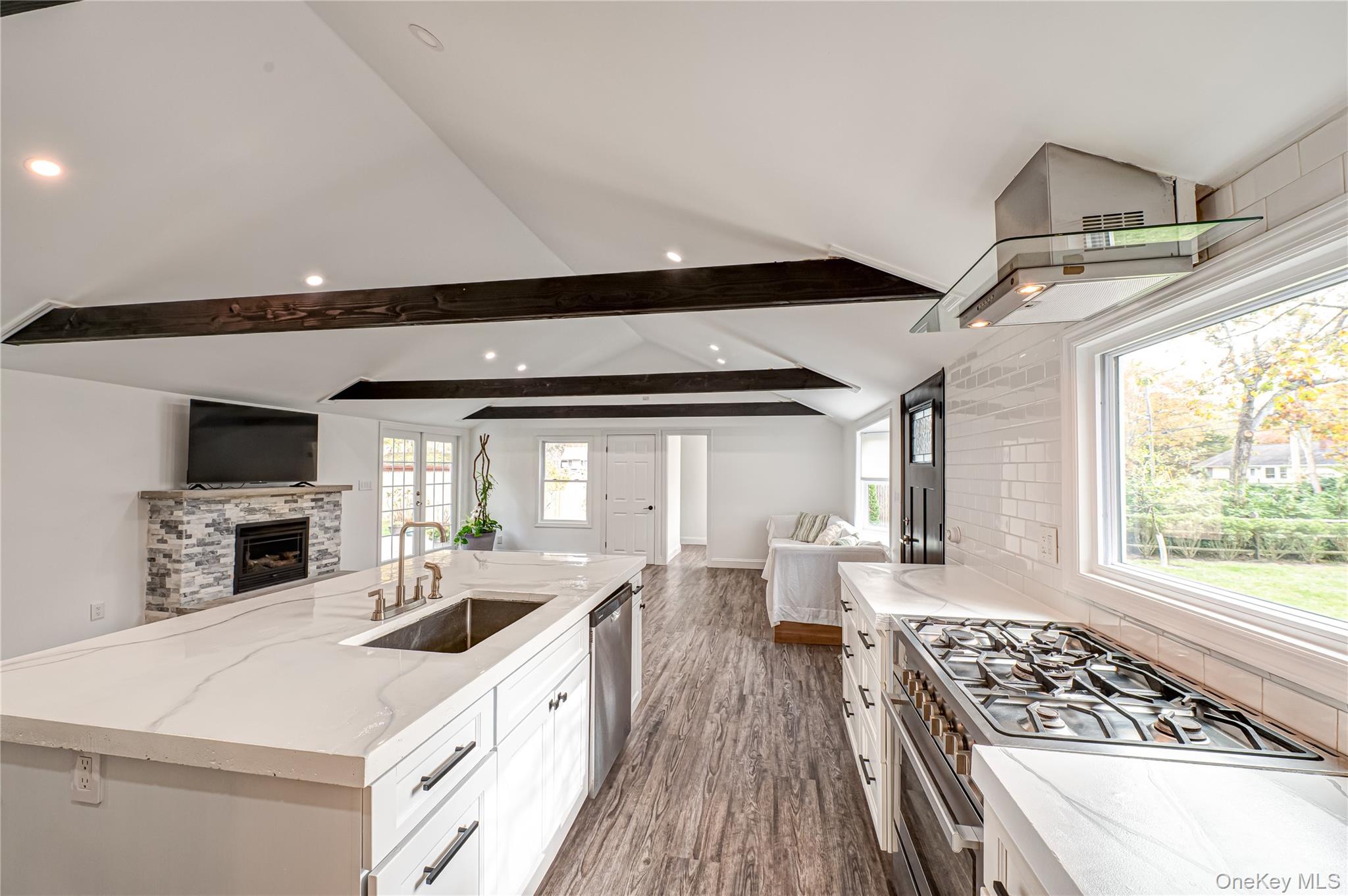 39 Lynncliff Road Hampton Bays, NY 11946 - Photo 33 of 34 Kitchen featuring open floor plan, dark wood-type flooring, appliances with stainless steel finishes, a center island with sink, and light stone countertops