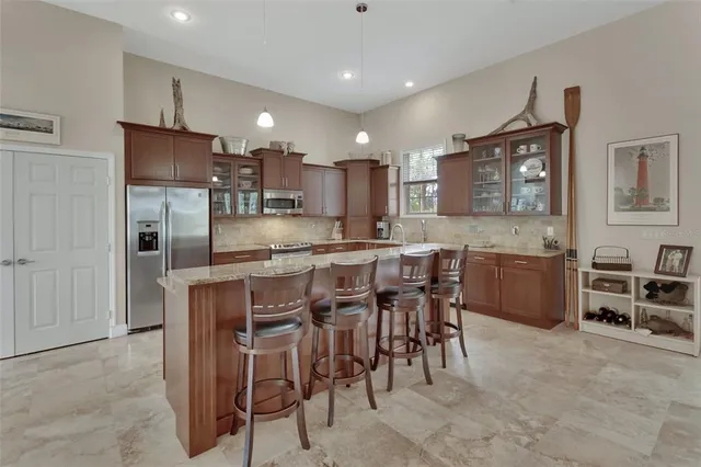 a kitchen with stainless steel appliances kitchen island granite countertop a refrigerator and a stove top oven