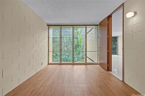 a view of an empty room with wooden floor and a window