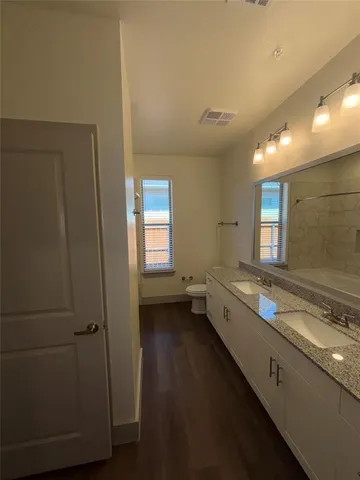 a large bathroom with a granite countertop sink a toilet and a vanity