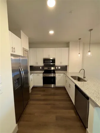 a large kitchen with granite countertop a refrigerator and a stove top oven
