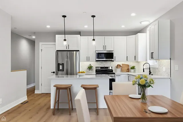 a kitchen with stainless steel appliances granite countertop a refrigerator a stove a sink dishwasher and white cabinets with wooden floor