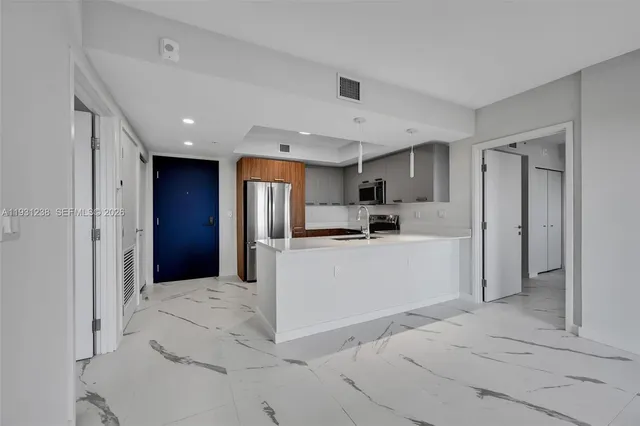a large white kitchen with kitchen island a sink stainless steel appliances and cabinets