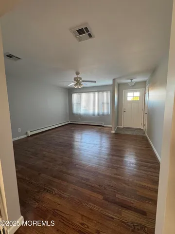 a view of an empty room with wooden floor and a window