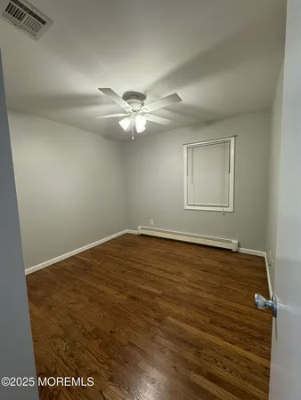 an empty room with wooden floor and fan