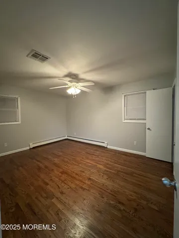 a view of an empty room with wooden floor and closet