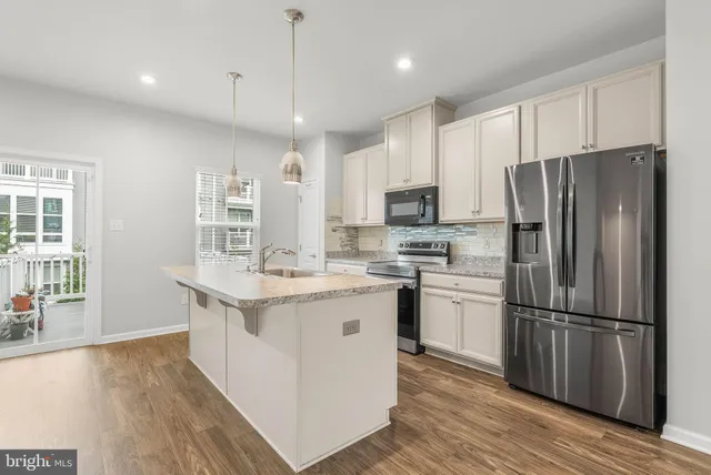 a kitchen with a refrigerator a sink cabinets and wooden floor
