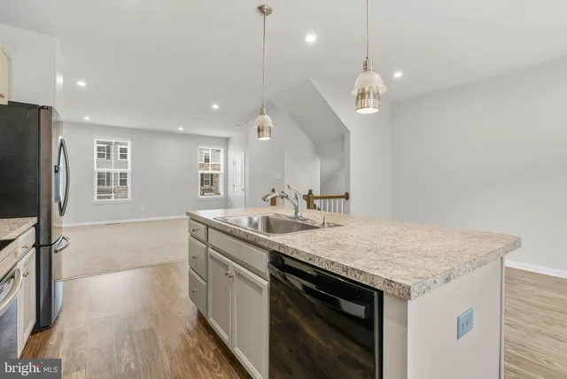 a kitchen with a sink a center island a wooden floor and a ceiling fan