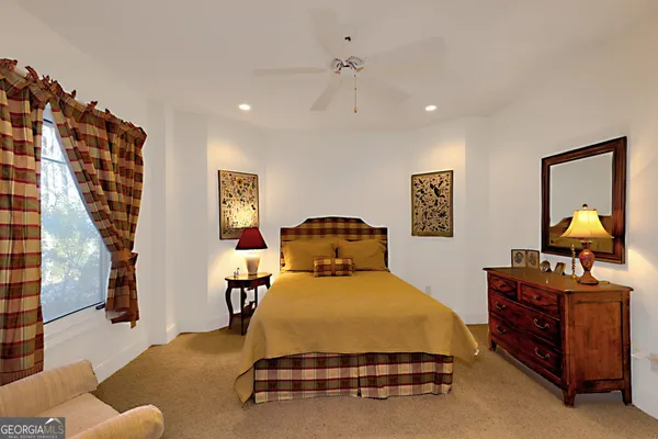 a view of a bedroom with cabinet a ceiling fan and a flat screen tv