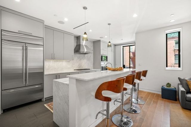 a kitchen with stainless steel appliances granite countertop a refrigerator a sink a stove and a dining table with wooden floor