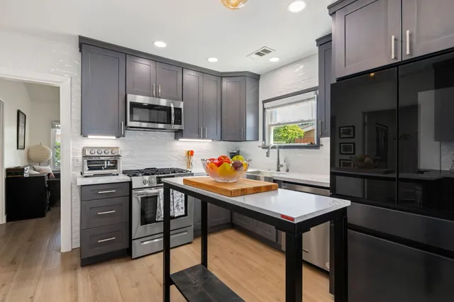 a kitchen with stainless steel appliances granite countertop a stove refrigerator sink microwave and cabinets